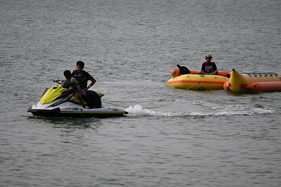 Personne tractée sur une bouée banane gonflable derrière un jet-ski, animation nautique événementielle