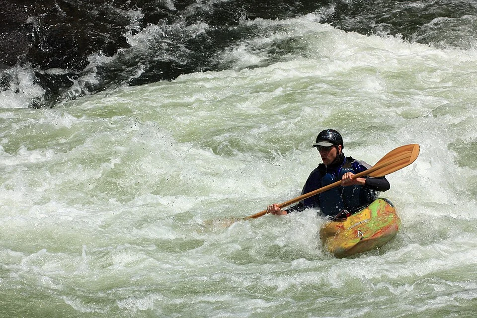Pratiquant de kayak pagayant en pleine rivière, animation canoë-kayak